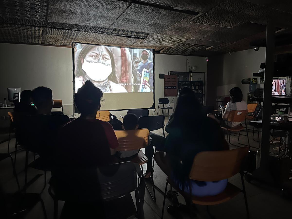 Imagem mostra participantes do cineclube assistindo o documentário Mensageiras da Amazônia