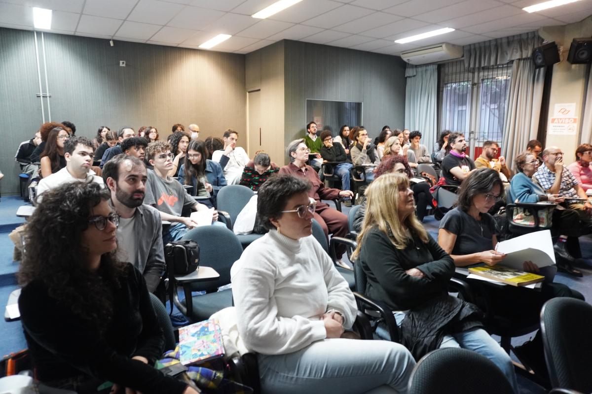 Participantes da mesa-redonda "Enciclopédias digitais em ação: artesanias, tecnologias, colaborações", assistem ao trailer de “Mapear Mundos”