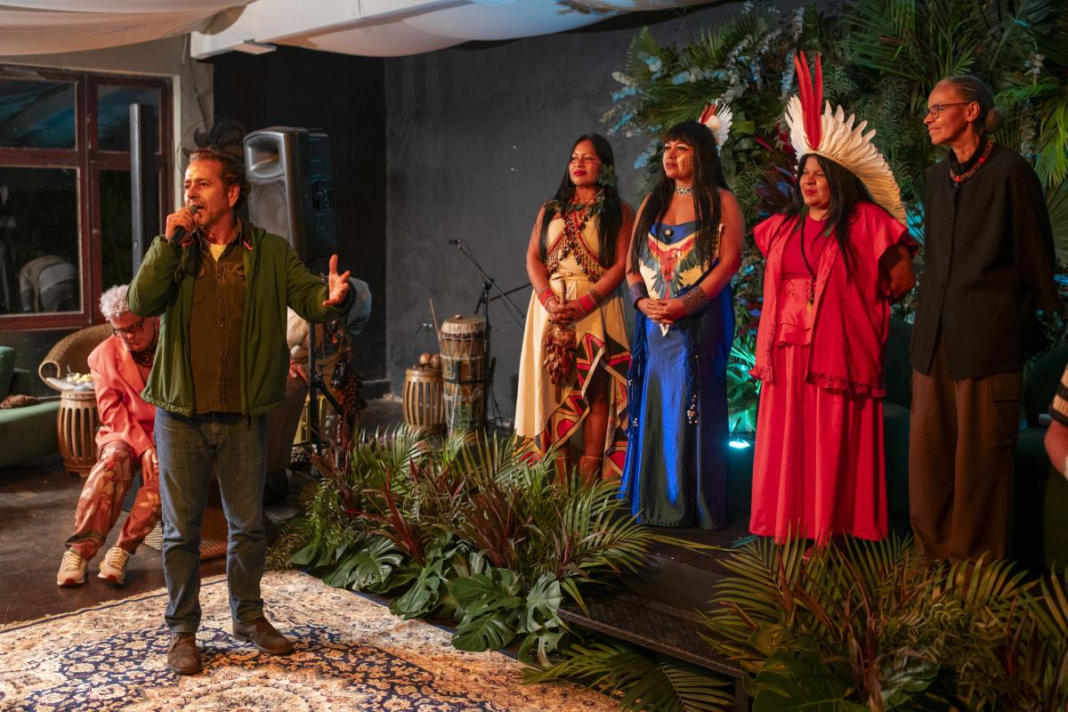 Marcos Palmeira fala ao microfone. Atrás dele estão Célia Xacriabá, Sonia Guajajara e Marina Silva