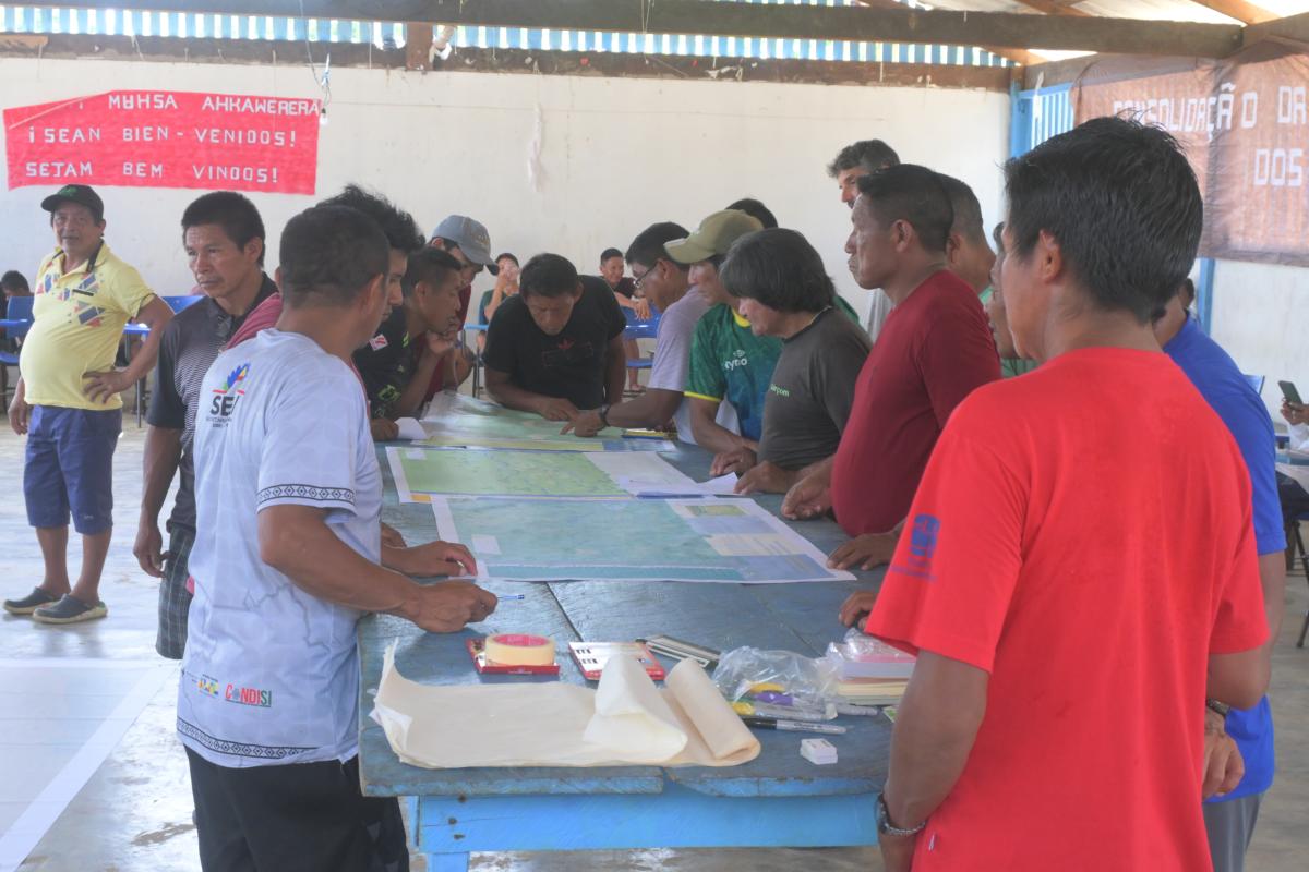 Fotos dos participantes do encontro em volta de um mapa em uma mesa