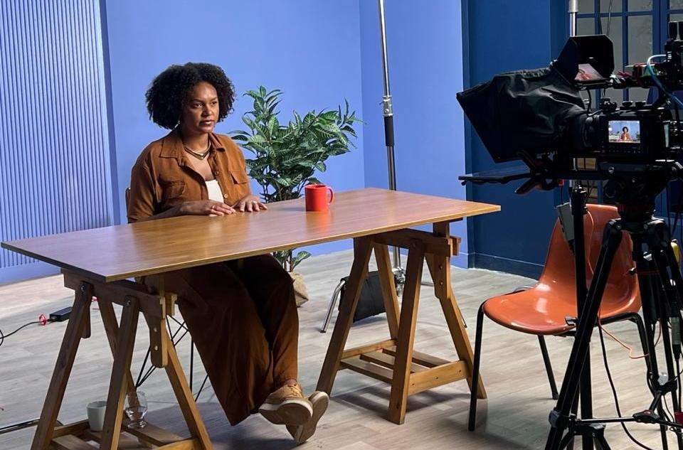 Jessie Alves sentada no estúdio durante a gravação do curso Clima e Sociobiodiversidade: formulando soluções de futuro