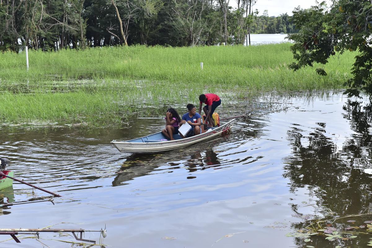 A foto mostra três pessoas em uma canoa navegando por um rio da Comunidade Quilombola de Boa Vista