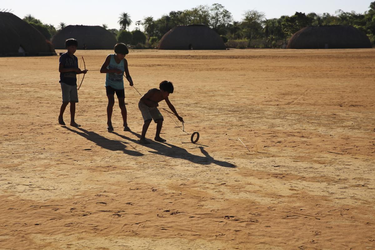 Na Aldeia Kalapalo, crianças se divertem com o ‘ta’, brincadeira que consiste em acertar uma flecha no centro de uma roda em movimento 