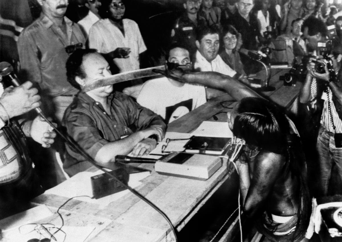 Tuíre Kayapó, liderança e guerreira kayapó, confronta com um facão o diretor da Eletronorte, José Antonio Muniz, contra os projetos de construção de hidrelétricas na região do Xingu, durante o I Encontro dos Povos Indígenas do Xingu, em 1989